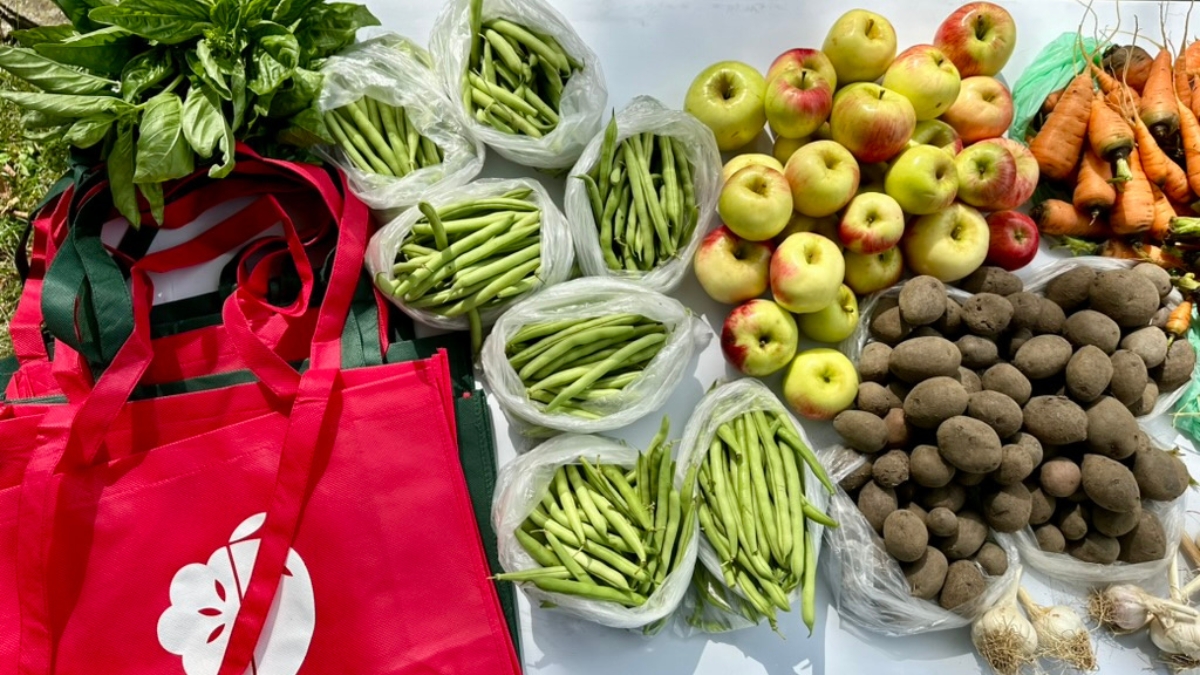 Tote bags next to assortment of fresh fruits and vegetables.